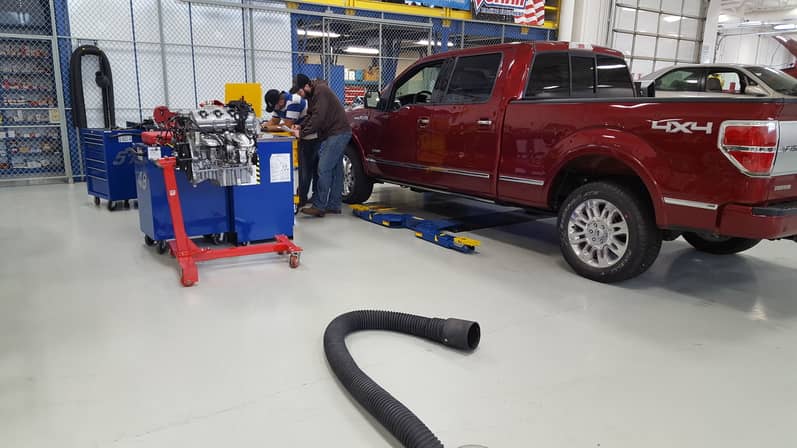Students in garage working on red Ford truck